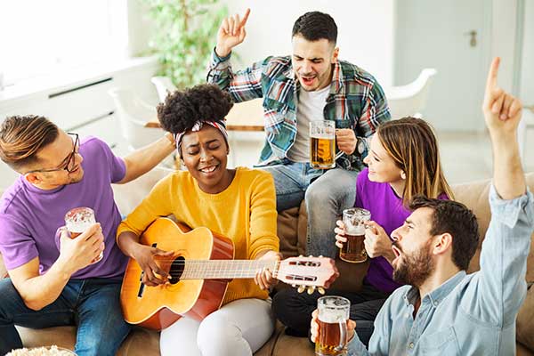 Friends playing guitar, singing and drinking beer